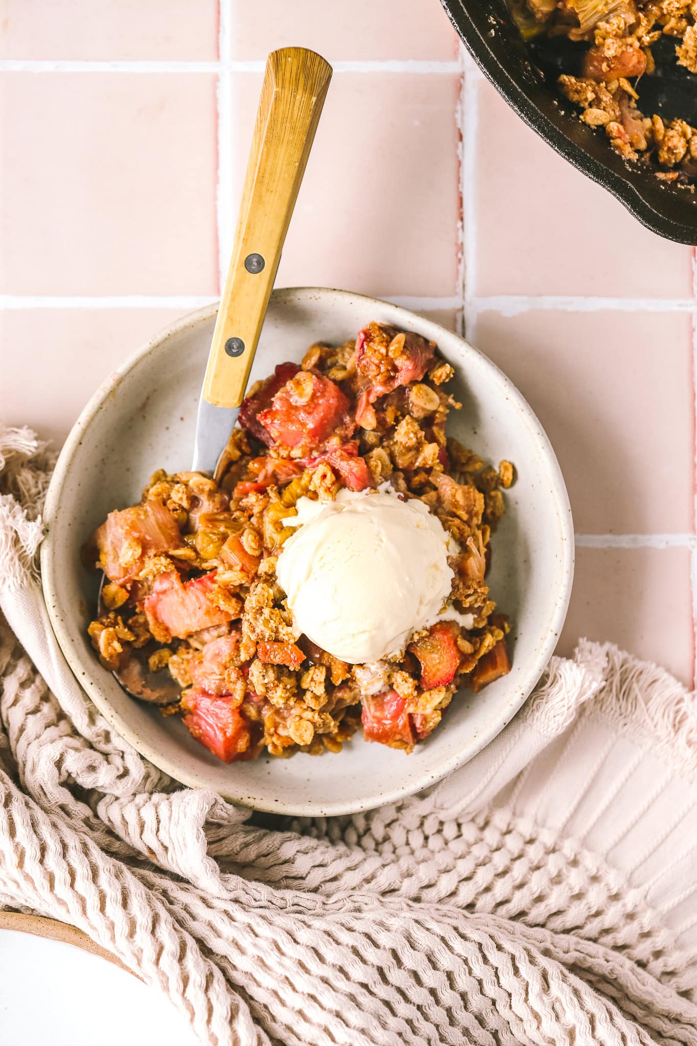 overhead shot rhubarb crisp in a bowl with ice cream
